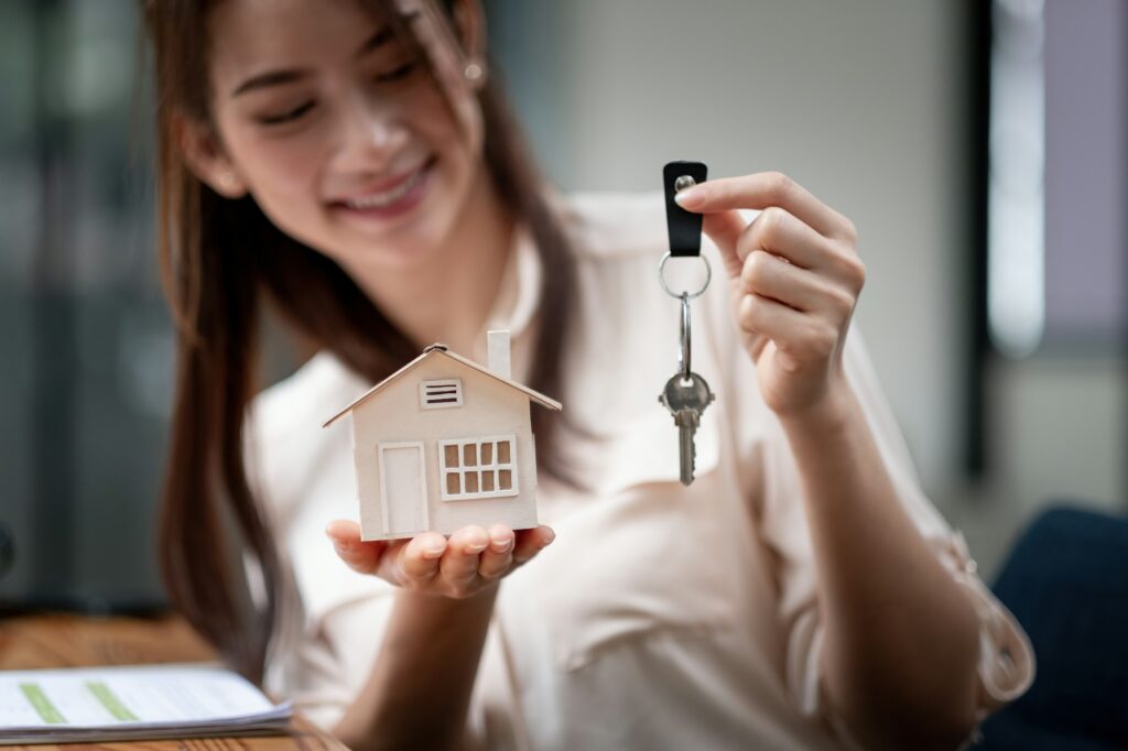 mortgage, real estate and property concept - close up of hands holding house model and home keys at